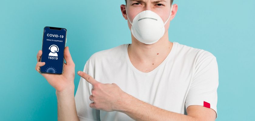 Man with a face mask holding an iPhone mockup