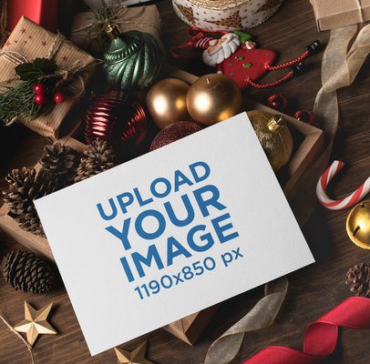 Christmas card mockup online: card on a flat lay with red ribbon, pine cones and gold ornaments