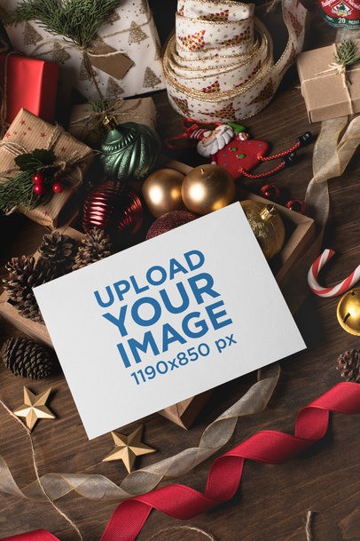 Christmas card mockup online: card on a flat lay with red ribbon, pine cones and gold ornaments