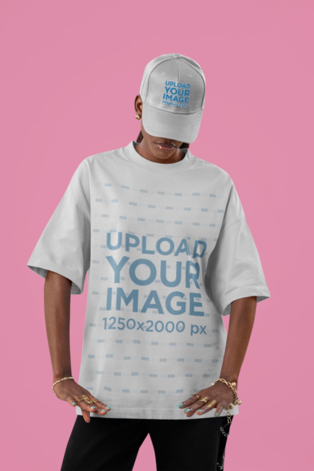 Customizable t-shirt mockup of a woman in an oversized white tee and dad hat against a pink studio background