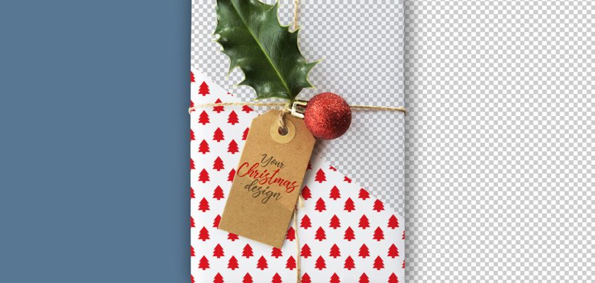 Free gift box mockup PSD: Christmas present with kraft tag, holly and red bauble on an editable background